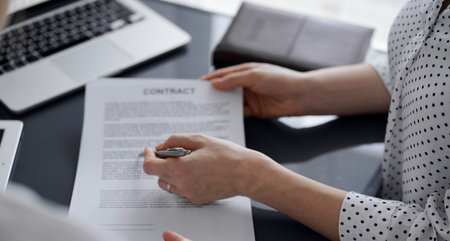 Business people sitting and discussing contract in office, closeup. Partners or lawyers working together at meeting. Teamwork and partnershipの写真素材