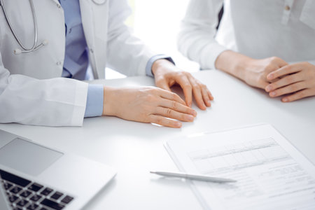 Doctor and patient discussing current health questions while sitting near of each other and using clipboard at the table in clinic, just hands closeup. Medicine conceptの写真素材