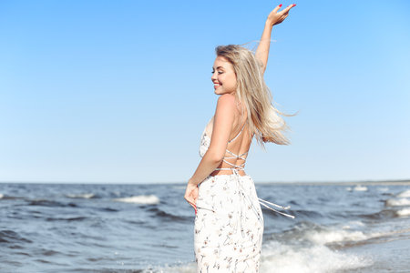 Happy blonde woman in free happiness bliss on ocean beach standing straight and posingの写真素材