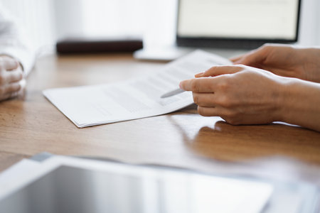 Businesswoman lawyer pointing into contract special points admitting something for colleague or client at the wooden desk in office. Business people teamwork and partnership, meeting conceptの写真素材