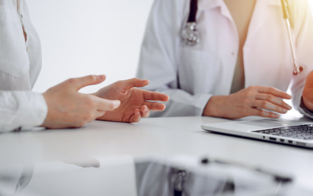 Doctor and patient discussing current health examination while sitting at the desk in clinic office, closeup. Perfect medical service and medicine conceptの写真素材