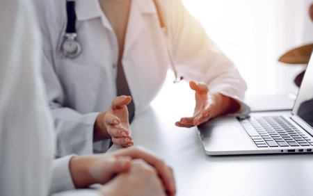 Doctor and patient discussing current health examination while sitting at the desk in clinic office, closeup. Perfect medical service and medicine conceptの写真素材
