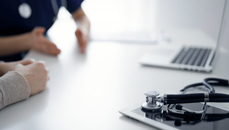 Stethoscope lying on the tablet computer in front of a doctor and patient at the background....