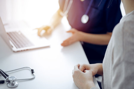 Doctor and patient talking to each other during current health examination while sitting at the desk in clinic, closeup of hand. Perfect medical service and medicine conceptの写真素材