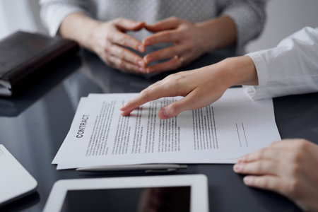 Business people discussing contract signing deal while sitting at the glass table in office, closeup. Partners or lawyers working together at meeting. Teamwork, partnership, success conceptの写真素材