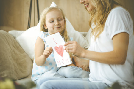 Happy mother day. Child daughter congratulates mom and gives her postcard with heart drawing. Family and childhood conceptsの写真素材