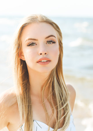 Happy blonde woman in free happiness bliss on ocean beach standing straight and posingの写真素材