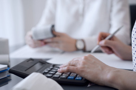 Two accountants use a calculator and laptop computer for counting taxes or revenue balance. Business, audit, and taxes conceptsの写真素材