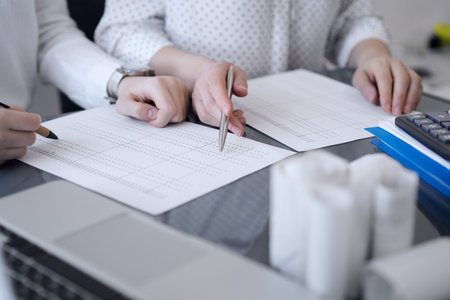 Two accountants use a calculator and laptop computer for counting taxes or revenue balance. Business, audit, and taxes conceptsの写真素材