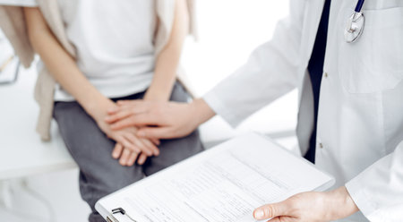 Doctor and child patient. The physician is holding clipboard and reassuring a boy. The concept of ideal health in medicineの写真素材
