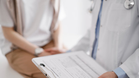 Doctor and patient discussing health exam results. Friendly physician reassuring a young woman by one hand while keeping clipboard with medical papers in another. Medicine conceptの写真素材