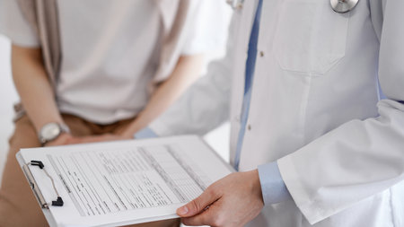 Doctor and patient discussing perfect health exam results. Friendly physician keeping with hands clipboard with medical papers near young woman. Medicine conceptの写真素材