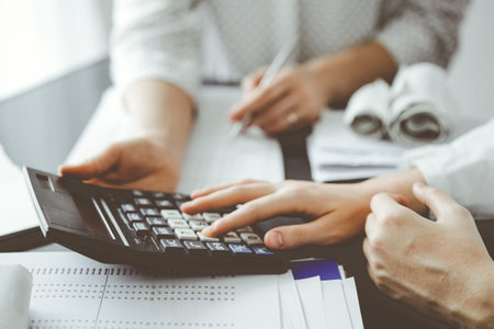 Woman accountant using a calculator and laptop computer while counting taxes for a client. Business audit and finance conceptsの写真素材