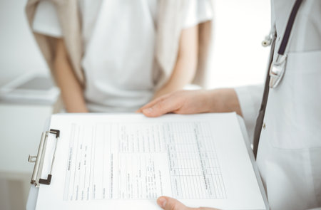 Doctor and child patient. The physician is holding clipboard with medication history records form near a boy. The concept of ideal health in medicineの写真素材