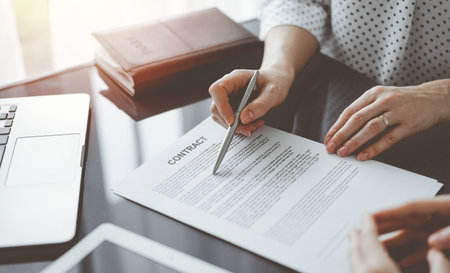 Business people signing contract papers while sitting at the glass table in office, closeup. Partners or lawyers working together at meeting. Teamwork, partnership, success conceptの写真素材