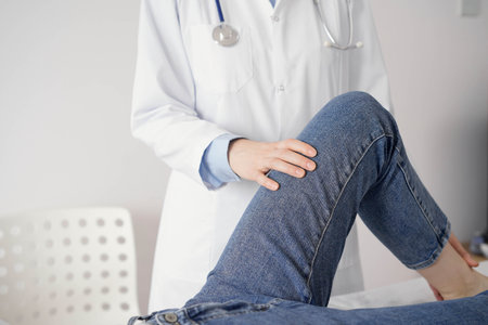 Doctor and patient are at the usual medical inspection in the clinic. Therapist examines a young womans knee. Medicine conceptの写真素材