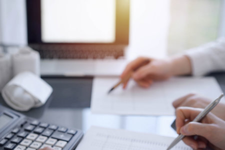 Two accountants use a calculator and laptop computer for counting taxes or revenue balance. Business, audit, and taxes conceptsの写真素材