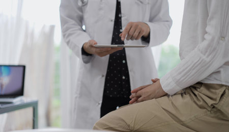 Doctor and a patient. The female physician is using a tablet computer besides a young woman during a consultation in the clinic, view above. Medicine conceptの写真素材