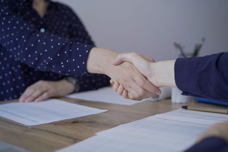 Accountants or auditors shaking hands after reviewing financial documents in office. Audit and...