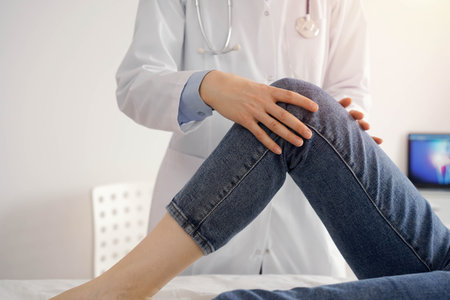 Doctor and patient are at the medical inspection in clinic. Orthopedic examines the knee of a young...