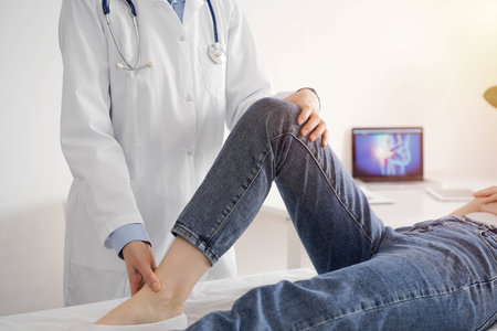 Doctor and patient are at the medical inspection in clinic. Orthopedic examines the knee of a young...