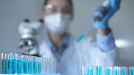 Close up of a female scientist researcher hand using a micropipette to fill up test tubes with a...