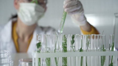 Woman scientist and researcher, wearing a lab coat, green protective gloves and face mask holding a...