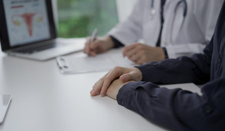 Doctor and a patient in clinic. The female physician is filling up medication history record form,...