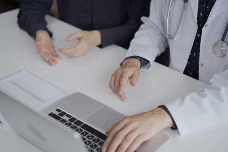 Doctor and a patient are discussing health while sitting in clinic. The female physician is using...