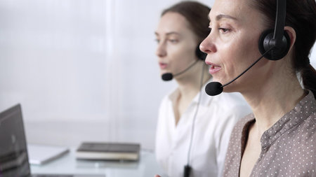 Focused female call center operator is assisting clients online, providing customer support and...