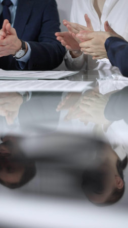Business partners or lawyers are applauding and celebrating achievements at glass table after successful meeting in office, vertical close up view. Concept of successの写真素材