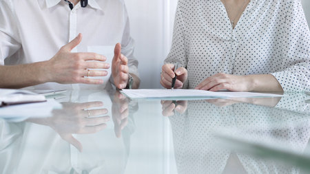 Business colleagues reviewing a contract, engaging in negotiations and strategic decision making in modern glass office, white casual dress style. Businesspeople conceptの写真素材