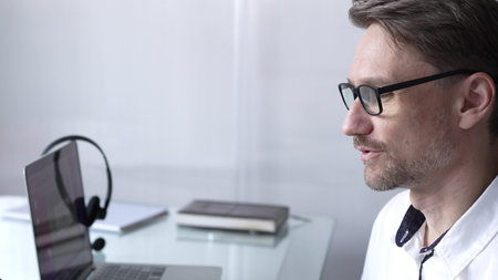 Businessman office worker attending online meeting using laptop and microphone, working remotely...