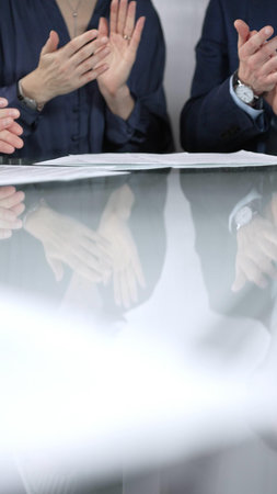 Business people applauding and celebrating achievements at glass table after successful meeting in...