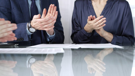 Unrecognizable business professionals applauding and celebrating achievements at glass table after...