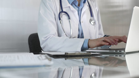 Doctor woman, wearing a blue blouse under a medical coat, is using technology in healthcare, close...