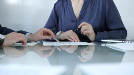 Business people or lawyers reviewing and discussing contract during a meeting, using a laptop and documents on a glass table. Businesspeople conceptの写真素材