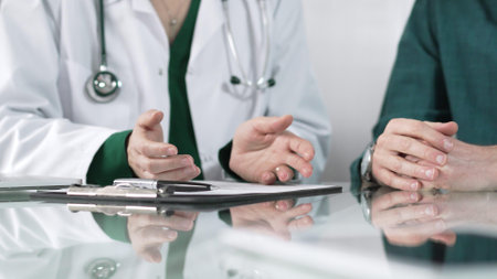Doctor using hand gestures to explain diagnosis to patient during medical consultation, providing support and guidance for healthcare decisionsの写真素材