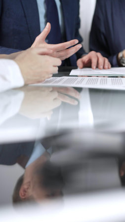 Business people are discussing a contract during meeting while sitting at the glass table in office, vertical close up view. Concept of success and team workの写真素材