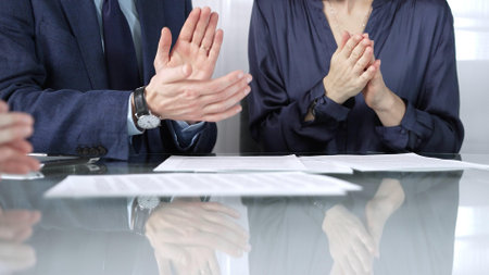 Unrecognizable business professionals applauding and celebrating achievements at glass table after successful meeting and contract signing. Business people concept, close up viewの写真素材