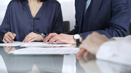 Business people reviewing contract terms while sitting at the glass desk during a meeting, negotiation in office, close up view. Success conceptの写真素材