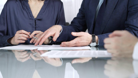 Business people reviewing contract terms while sitting at the glass desk during a meeting, negotiation in office, close up view. Success conceptの写真素材