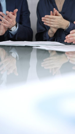 Business people applauding and celebrating achievements at glass table after successful meeting in office, vertical close up view. Concept of successの写真素材