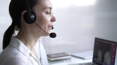 Adult female call center operator in assisting clients online, providing customer support and answering inquiries. Business call center conceptの写真素材