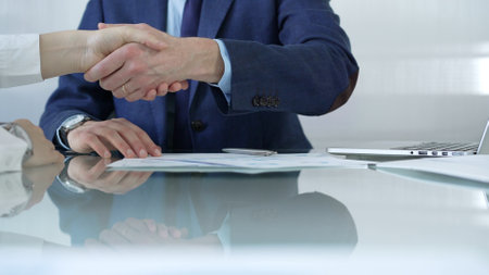 Business people shaking hands at the glass table after reaching an agreement during a meeting. Close-up of handshakeの写真素材