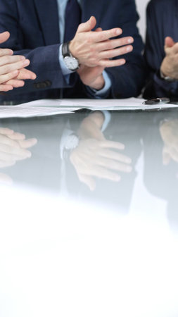 Business people applauding and celebrating achievements at glass table after successful meeting in office, vertical close up view. Concept of successの写真素材