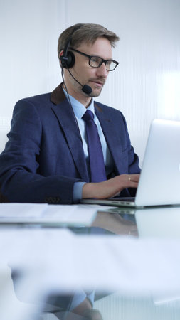 Businessman in blue suit is using a headset and laptop to offer customer service or online consultations. Business people conceptの写真素材