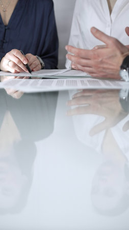 Business people are reviewing contract terms during a meeting, negotiating and making decisions together, vertical close up view. Copy space areaの写真素材
