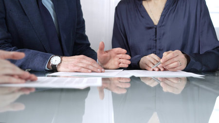 Business people reviewing contract terms while sitting at the glass desk during a meeting, negotiation in office, close up view. Success conceptの写真素材