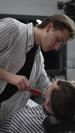 Professional barber trimming customers hair with electric clipper, focusing on precise nape grooming...